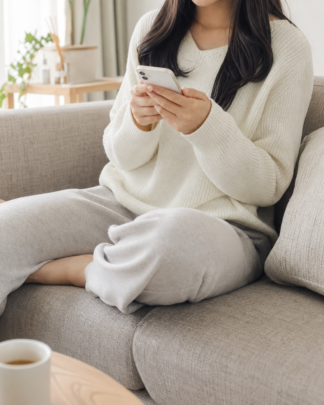自宅のソファでスマートフォンから応募する女性